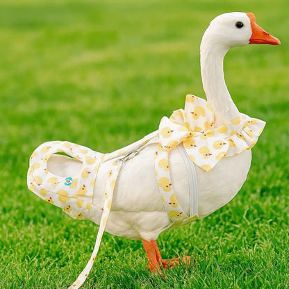 White banana ducks goose wearing a yellow duck decor dress, diaper and leash on a grassy field